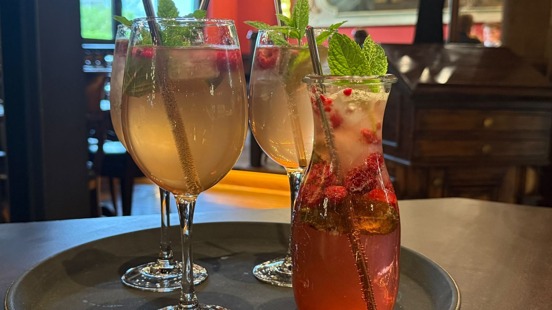 Spritz-Gläser mit Minze und eine Karaffe Himbeerlimonade auf dem Tablett