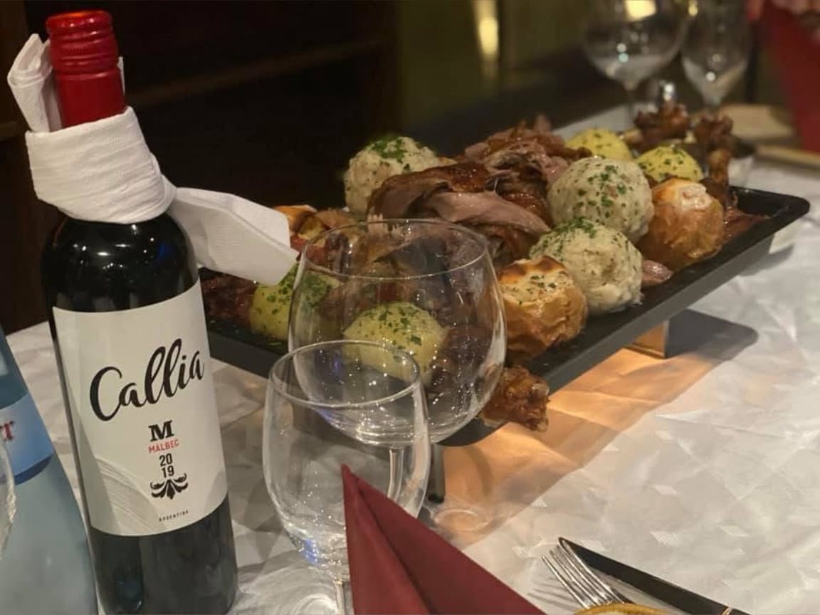 Gedeckter Tisch mit Rotwein und Grillplatte mit Knödeln