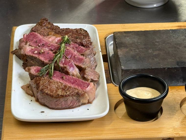 Aufgeschnittenes Steak mit Dip neben dem heißen Stein
